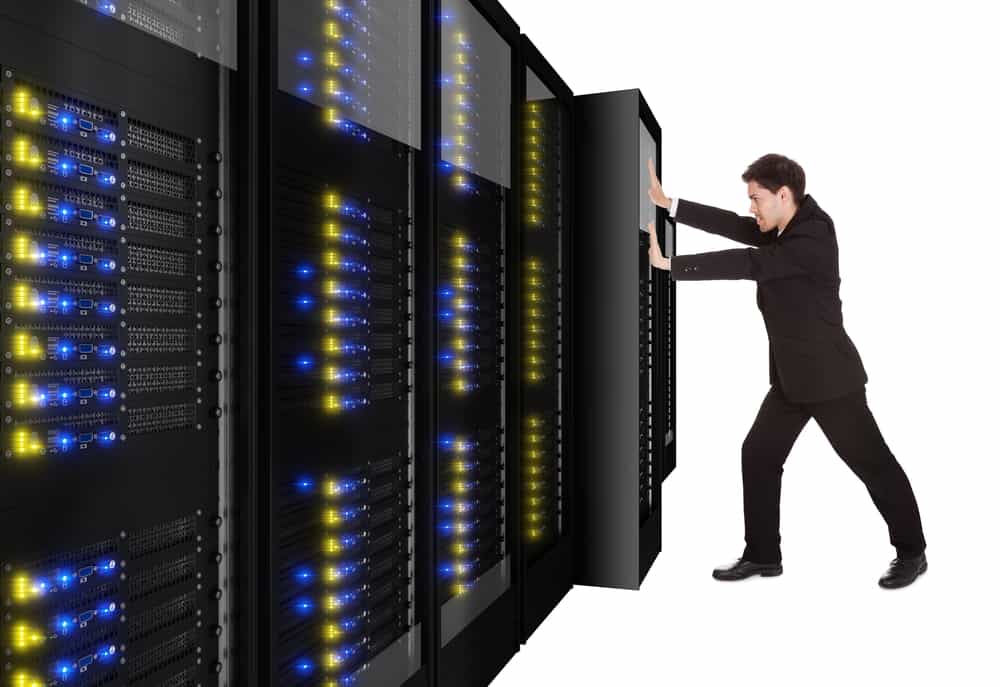 A data center migration is represented by a person physically pushing a rack of data center infrastructure into place A data center migration is represented by a person physically pushing a rack of data center infrastructure into place